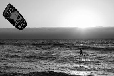 Man kiteboarding in sea against sky