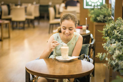 Young woman with coffee cup on table at cafe