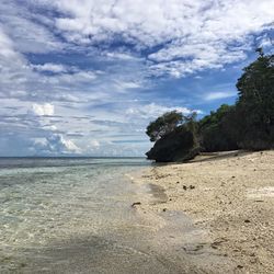 Scenic view of beach against cloudy sky