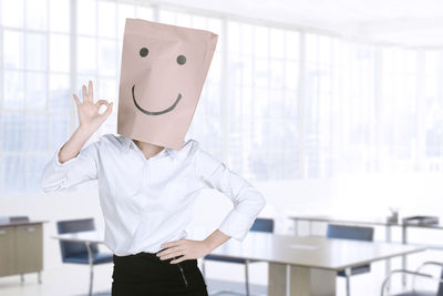 Businesswoman wearing paper bag with anthropomorphic face in office