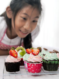 Close-up of girl looking at cupcakes on cooling rack