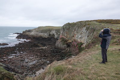 Rear view of man standing on mountain against sky