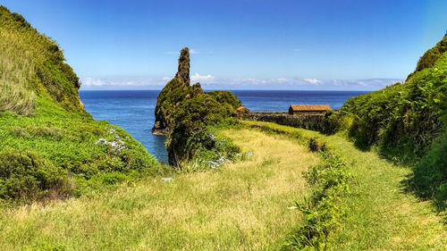 Picturesque panorama with a small picnic area by the sea with rocks and a green meadow