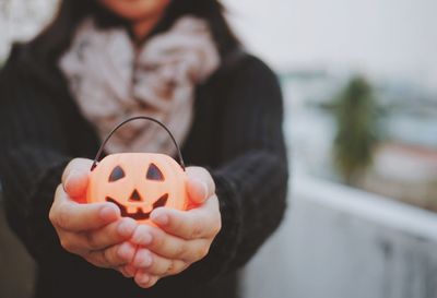 Midsection of woman showing jack o lantern toy during halloween