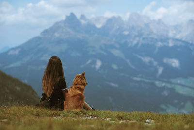 Woman with dog sitting on field