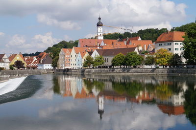 Buildings by lake against sky