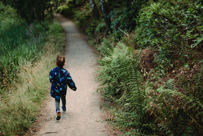 A young boys runs quickly along a path in the woods