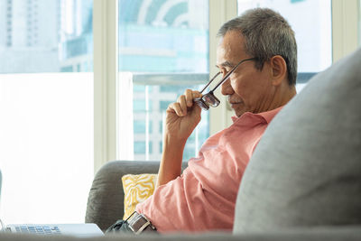 Midsection of man using mobile phone while sitting on sofa