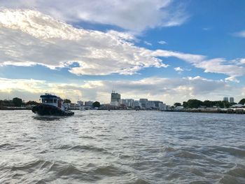 Sea by buildings in city against sky
