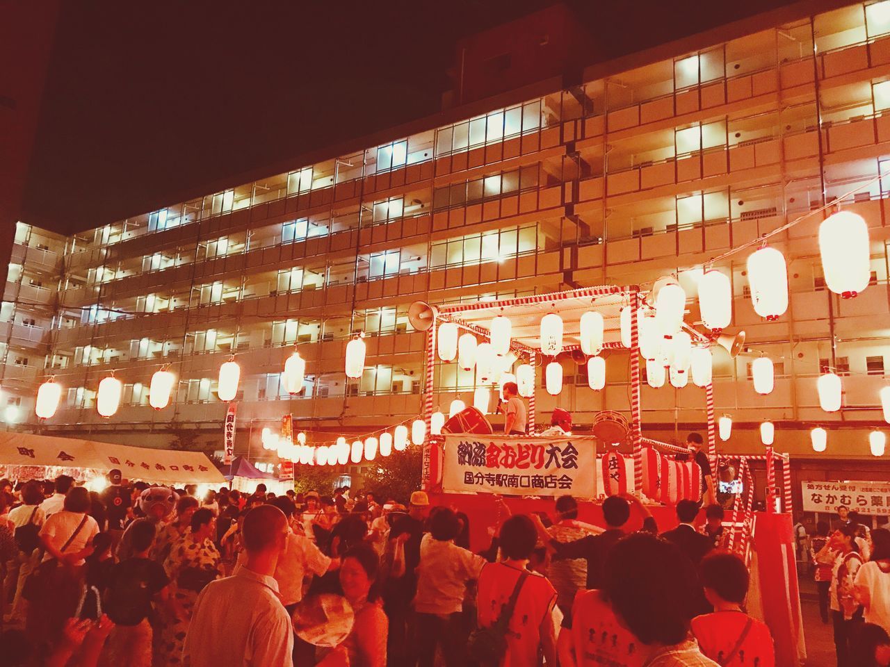 CROWD AT ILLUMINATED CITY AT NIGHT