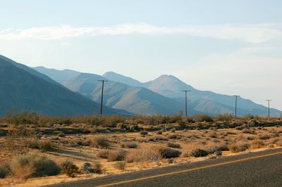 Scenic view of road by mountains against sky