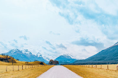 Road amidst field against sky