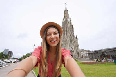 Portrait of young woman standing against clear sky