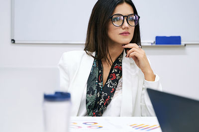 Portrait of young woman using mobile phone in office