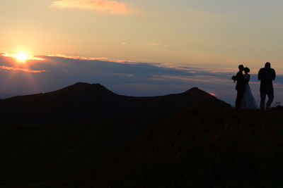 Silhouette people standing on mountain against sky during sunset