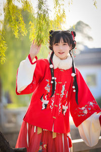 Portrait of young woman standing against trees