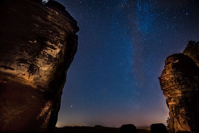 Low angle view of rock formations against star field at night