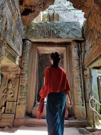 Rear view of woman standing in old ruin temple