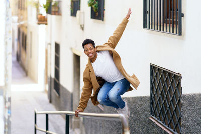 Portrait of smiling young woman standing on railing