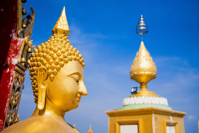 Close-up of buddha statue against blue sky