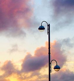 Low angle view of street lights against cloudy sky at sunset