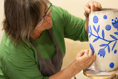 Artisan making design on earthen pot at pottery workshop