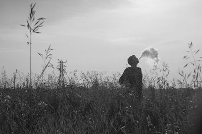 Young woman smoking on field against sky