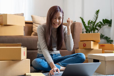 Young businesswoman clinching fist while using laptop at home