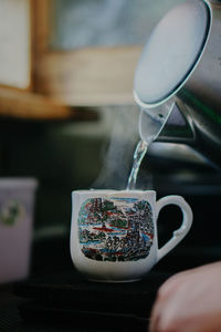 Close-up of hand holding tea cup on table