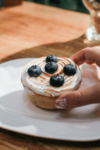 Cropped hand of woman holding dessert in plate on table