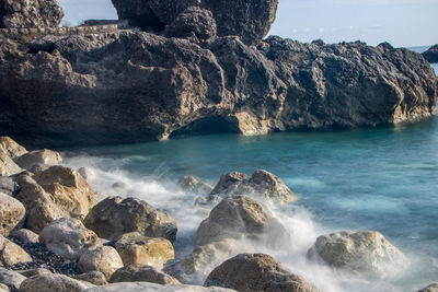 Scenic view of rocks in sea against sky