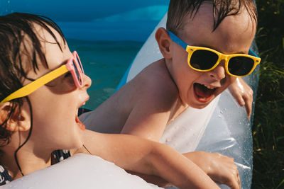 Portrait of cheerful laughing children in sunglasses in the swimming pool on a hot summer day. 