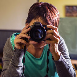 Woman photographing with digital camera at home