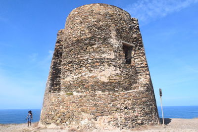 Woman by historical building against sea and sky