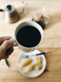 Close-up of hand holding coffee cup on table