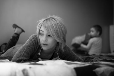 Close-up of thoughtful woman lying on bed at home