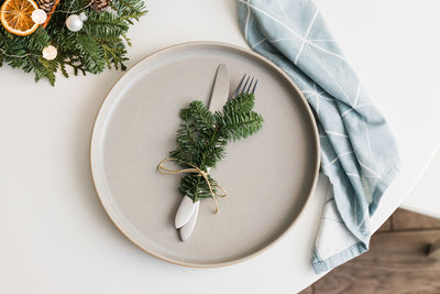 Top view of christmas or new year table setting with ceramic plate, fir branch with decor