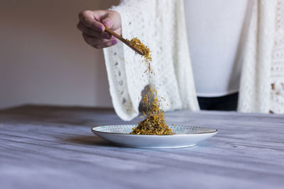 Person holding ice cream in bowl on table