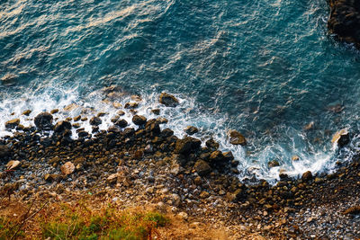 High angle view of sea waves splashing on rocks