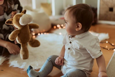 Boy playing with toy sitting on floor at home