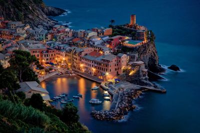 High angle view of illuminated buildings by sea
