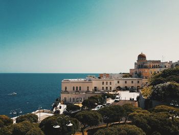 Buildings by sea against clear sky