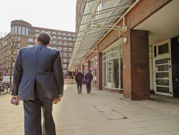 Rear view of people walking on street amidst buildings