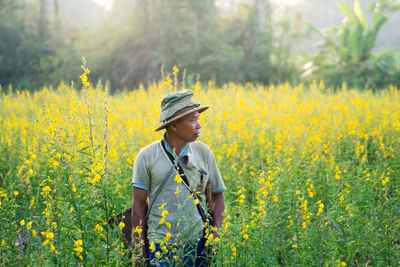 Man looking away while standing amidst plants on field