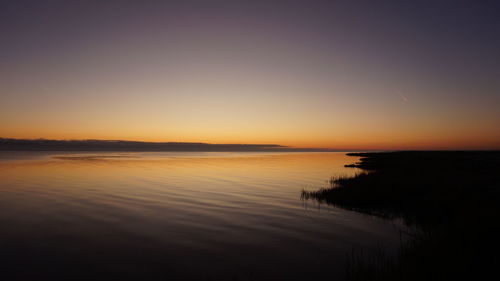 Scenic view of lake against clear sky at sunset