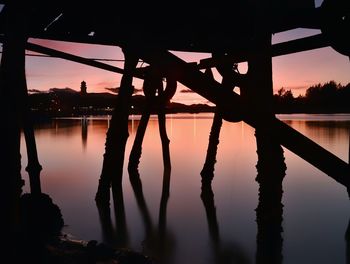 Reflection of silhouette trees in lake against orange sky