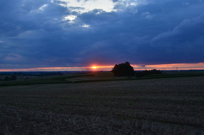 Scenic view of silhouette field against sky at sunset