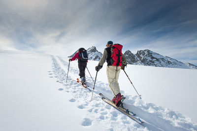 Rear view of people on snowcapped mountain against sky