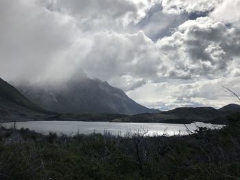 Scenic view of mountains and lake against cloudy sky