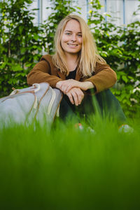 Portrait of smiling young woman with blond hair sitting on grass